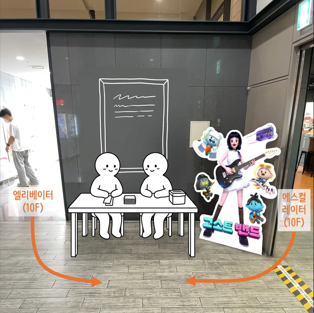 10층 로비 배부 테이블 위치 — 엘리베이터와 에스컬레이터 사이 포스터 벽 앞